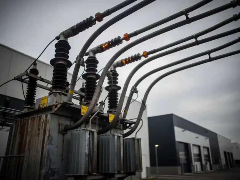 Dikke industriële stroomkabels onder zware belasting aangesloten op een transformatorstation bij een Nederlands commercieel magazijn.